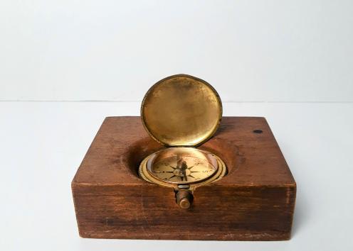 A brass compass mounted on a wooden box. 