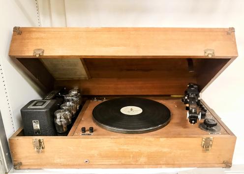 Record player in a wooden enclosed case. On the right is an oz needle pressure equipment, on the left is Thordarson choke coil. 