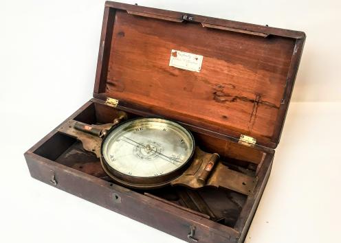 The compass measures 15~5/8” in length and is fit with a 6” needle and 7~ 3/8” sight vanes, a variation ard and slow motion tangent screw and two opposed bubbles mounted on the main-plate. The original staff mount is lacking; the original case is present and in good condition as is the original heavy lathe-turned lid.