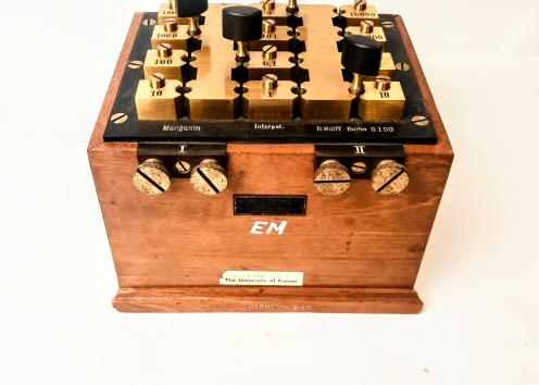 This is a variable resistor, also known as a "resistance box" or "potentiometer," and is used as a standard-value resistor for teaching, circuit prototyping, or lab work.  Comes in a wooden case with 4 dials. 